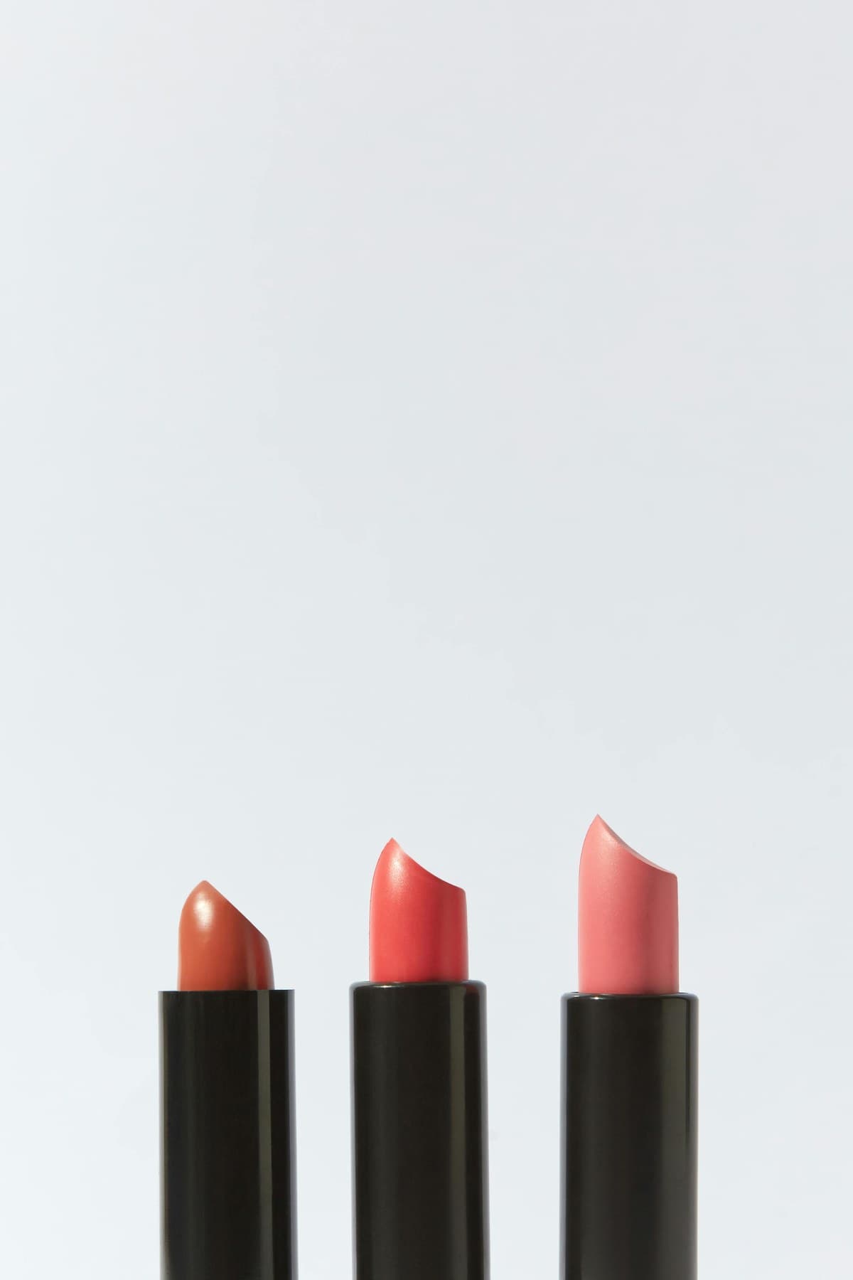 Three lipstick bullets in warm nude and rose tones
